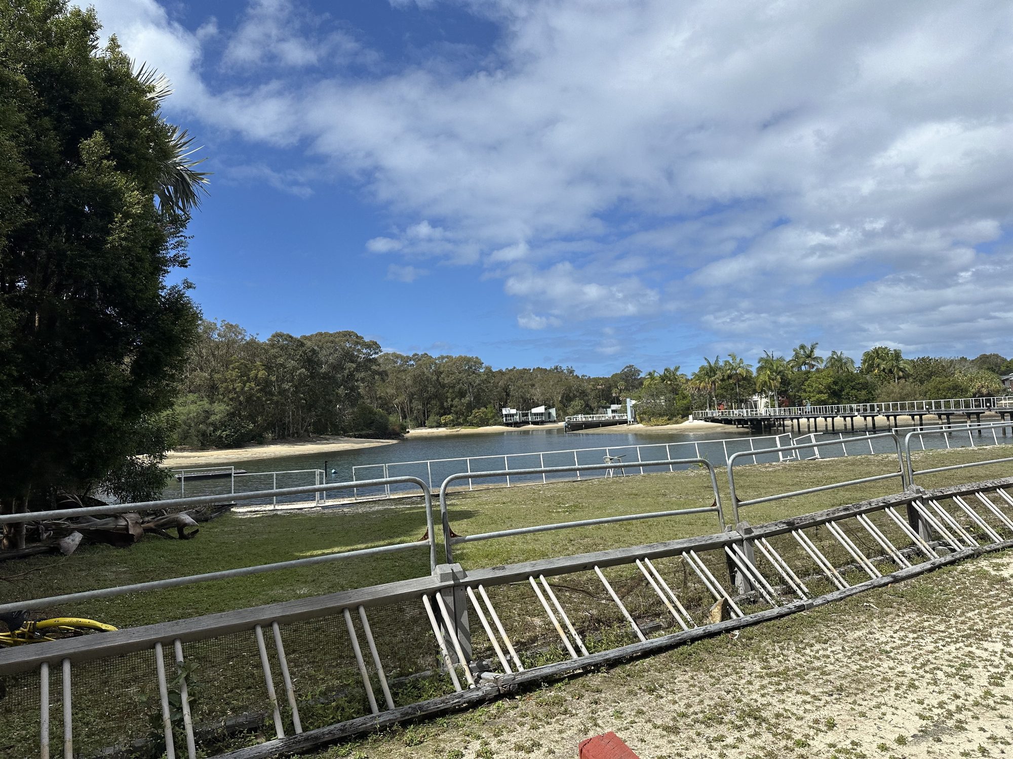View across the Couran Cove marina basin toward lodge buildings and a pedestrian bridge