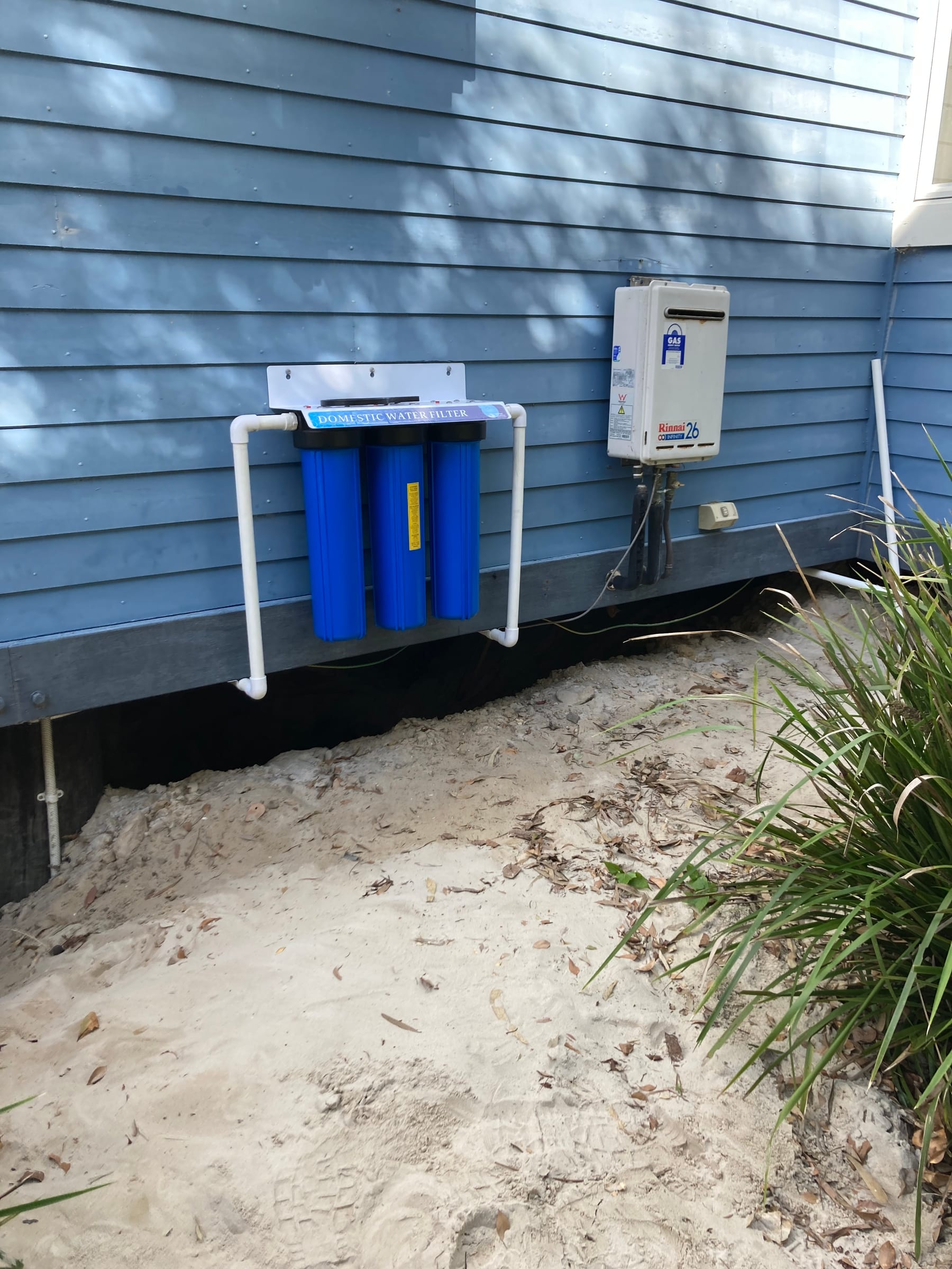 Domestic water filtration equipment and gas water heater mounted beside a blue building